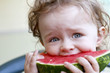 Small toddler eating melon