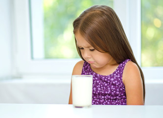 Wall Mural - Sad little girl with a glass of milk