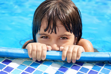 little girl with beautiful eyes peeking out of the pool