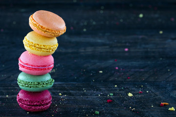 Colorful macaroons on a dark black wooden background