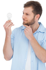 Poster - Sceptical model holding a bulb and touching his chin