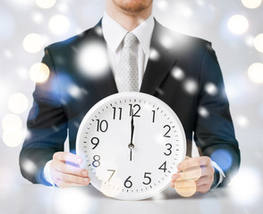 man holding wall clock showing 12