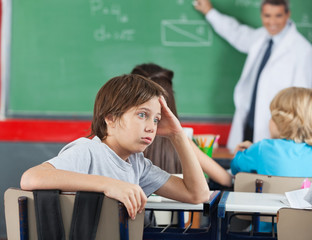 Shocked Little Boy Sitting At Desk