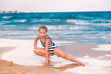 Beautiful little girl excercising on the beach