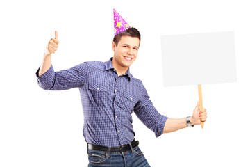 Wall Mural - Handsome guy with party hat holding a panel and giving thumb up