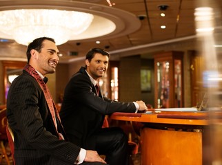 Two young men in suits behind table in a casino