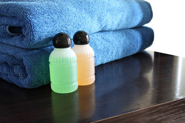 Spa bottles and blue towel on wooden table.