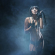 A young and sexy woman in fetish lingerie on a spooky background