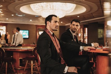 Two young men in suits behind table in a casino