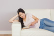 © WavebreakmediaMicro - Pretty asian girl lying on the sofa reading book