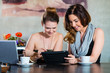 © Kzenon - women sitting in restaurant with Tablet Computer