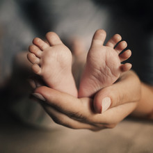 Mother Hold Feets Of Newborn Baby