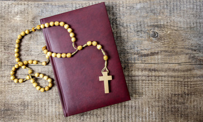 Wall Mural - Holy Bible, rosary and red rose petals on wooden table. Copy spa