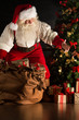 © Milles Studio - Santa putting gifts under Christmas tree in dark room