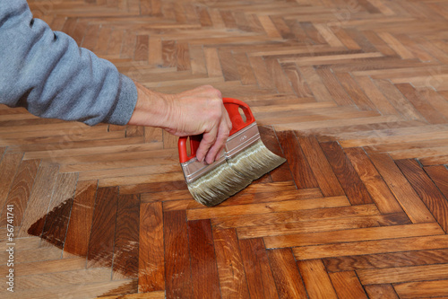Fotografía Varnishing of oak parquet floor, workers hand, brush, renovation