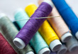 New spools of colourful thread with sewing needle