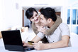 © Creativa Images - Young asian couple online shopping at home