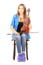 Casual Young Woman Seated On A Wooden Chair Holding A Violin