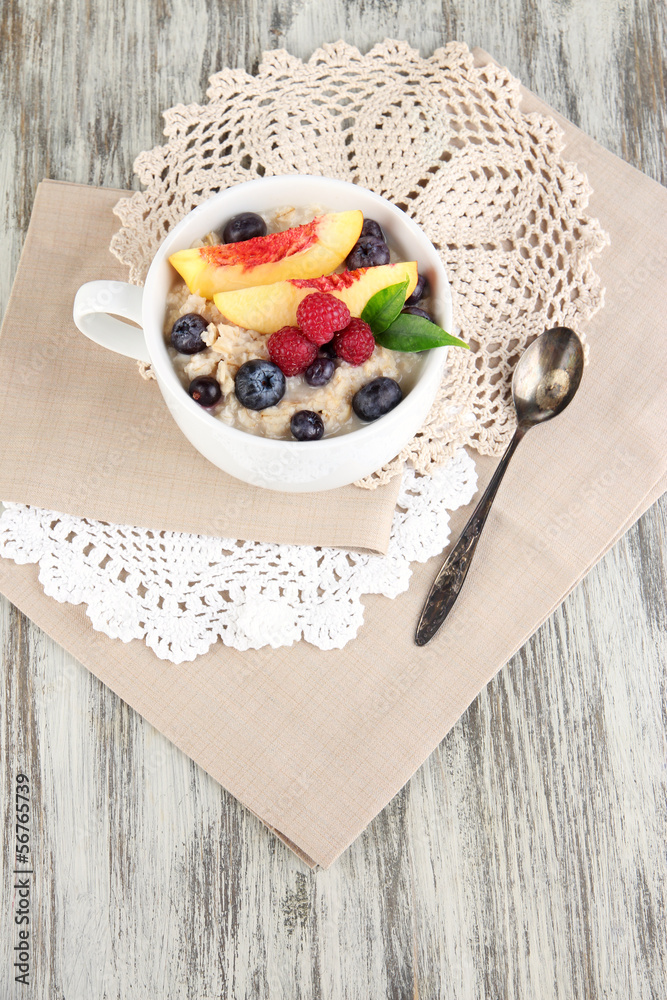 Oatmeal in cup with berries on napkins on wooden table