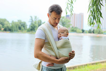 Father Carrying His Son In Sling Outdoors
