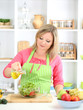 © Africa Studio - Happy smiling woman in kitchen preparing vegetable salad