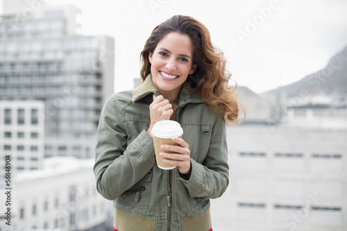 Fotografia Cheerful gorgeous brunette in winter fashion holding disposable