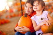 Adorable Little Girls Holding Pumpkins At A Pumpkin Patch