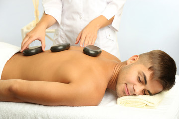 Canvas Print - Young man having stone massage in spa salon