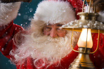 Santa Claus is holding a shining lantern while sneaking to his h