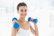© lightwavemedia - Pleased natural brown haired woman in white sportswear lifting d