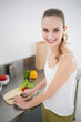 © lightwavemedia - Happy young woman preparing vegetables smiling at camera