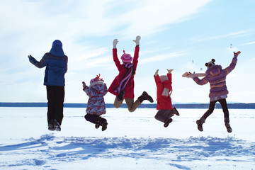 Group of cheerful children jumping in the snow in winter