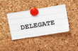© thinglass - The word Delegate on paper note pinned to a cork notice board
