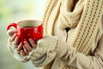 Female hands with hot drink, on light background