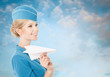 Charming Stewardess Holding Paper Plane In Hand. Blue Sky Backgr