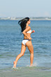 © M-Production - Sensual brunette running on the beach. From the back.