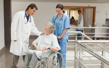 Wall Mural - Nurse and doctor talking with old woman in wheelchair