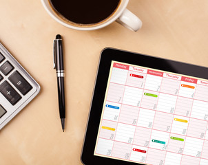 Wall Mural - tablet pc showing calendar on screen with a cup of coffee on a d