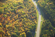 Aerial view of road curving through woods in fall color