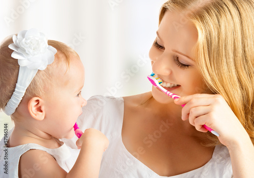 Fotografía mother and daughter baby girl brushing their teeth together