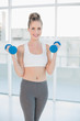 © lightwavemedia - Happy athletic blonde exercising with dumbbells