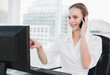 © lightwavemedia - Happy businesswoman sitting at desk talking on smartphone pointi