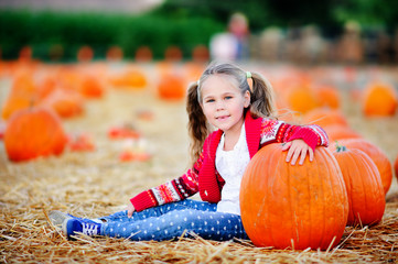 happy toddler girl picking a pumpkin for halloween