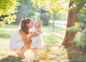 Wall Mural - Portrait of happy mother and baby playing outdoors