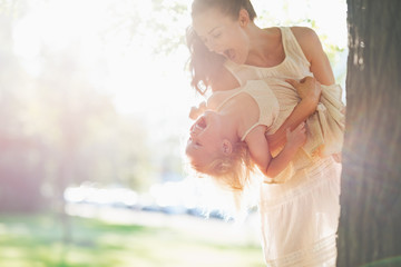 Wall Mural - Happy mother and baby having fun near tree