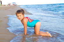 A Little Girl In Blue Swimsuit  Plays On The Beach