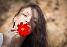 Portrait Of Beauty Young Woman With Red Flower In Her Mouth.