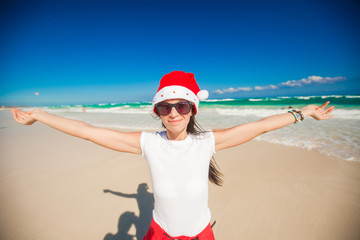 Poster - Young woman in Santa Hat walking spread her hands on white sandy