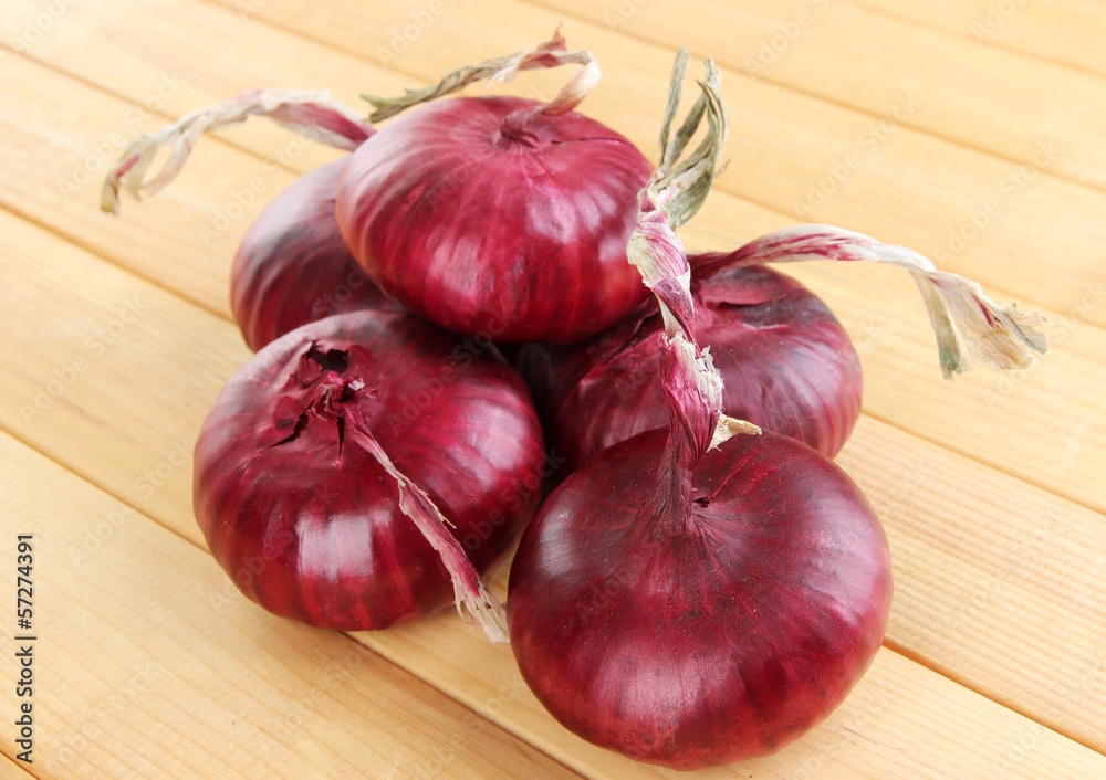 Fresh red onions on wooden table