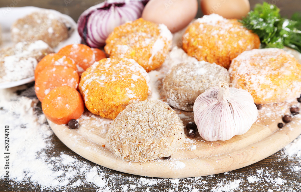 Meat patties on board on wooden table